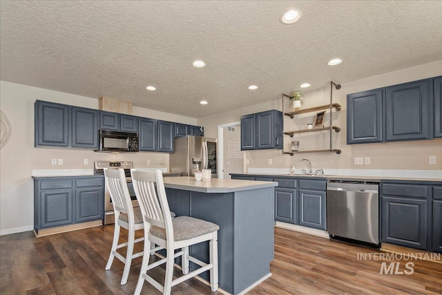 9308 W Rustica Dr, Boise, ID 83709 - kitchen with appliances with stainless steel finishes, light countertops, a breakfast bar area, dark wood-style flooring, and a textured ceiling
