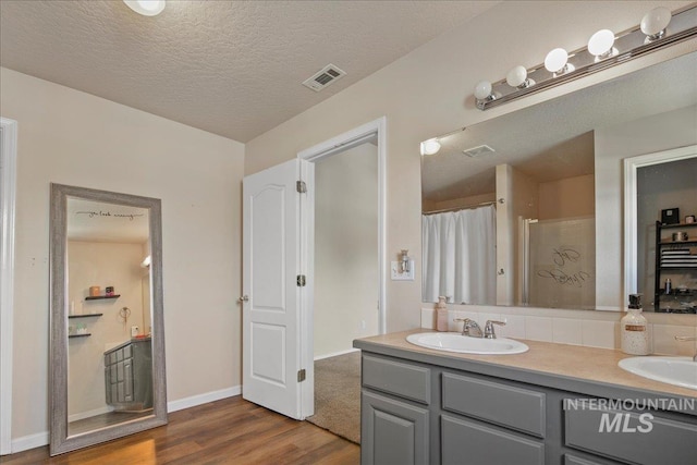 9308 W Rustica Dr, Boise, ID 83709 - bathroom with wood finished floors, double vanity, curtained shower, and a textured ceiling