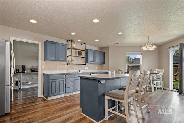 9308 W Rustica Dr, Boise, ID 83709 - kitchen with freestanding refrigerator, light countertops, dark wood-style floors, a breakfast bar, and a center island