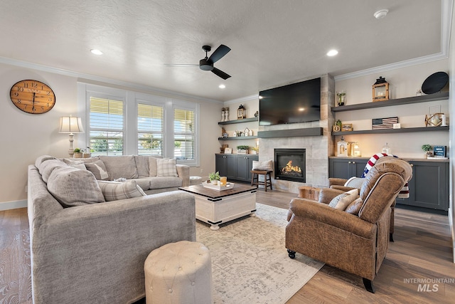 2245 N Burnam Ave, Star, ID 83669 - living room with crown molding, a fireplace, ceiling fan, recessed lighting, and light wood-style flooring