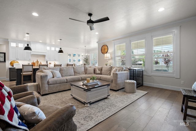 2245 N Burnam Ave, Star, ID 83669 - living area featuring crown molding, wood finished floors, baseboards, recessed lighting, and ceiling fan with notable chandelier