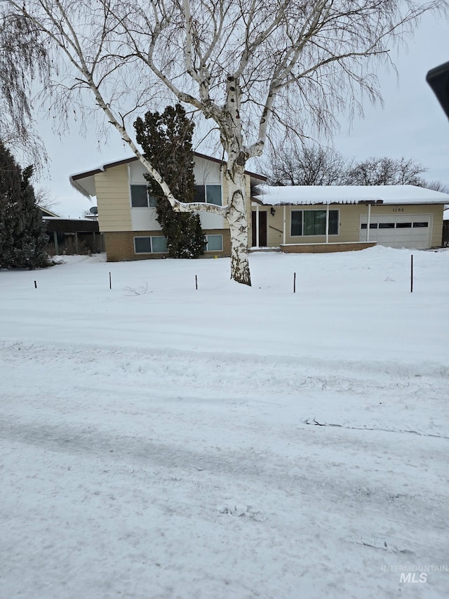 snowy yard featuring a garage