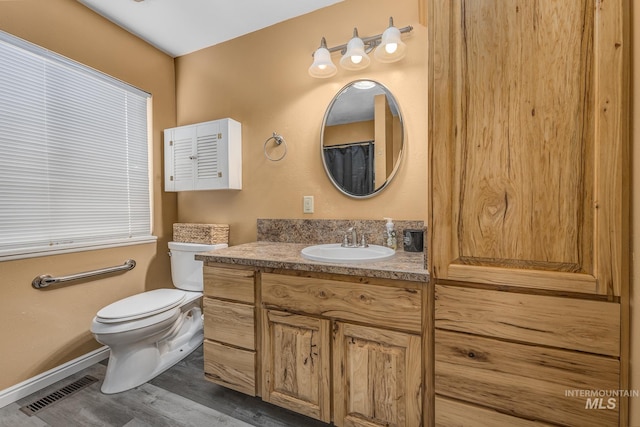 bathroom featuring toilet, wood finished floors, vanity, and visible vents