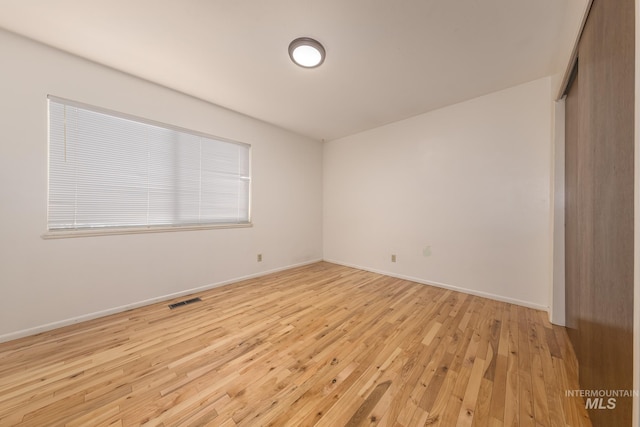 unfurnished bedroom with light wood-type flooring, baseboards, visible vents, and a closet