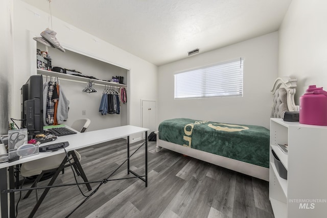 bedroom with a closet, visible vents, and wood finished floors