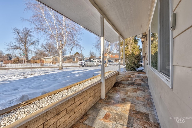 snow covered patio with a residential view and fence