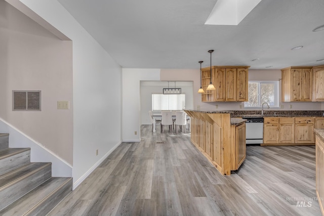 kitchen featuring a skylight, pendant lighting, light wood finished floors, visible vents, and dishwasher