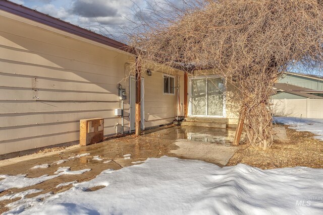 snow covered property entrance featuring fence