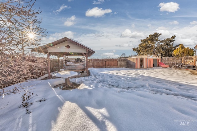 yard layered in snow featuring a fenced backyard and a gazebo