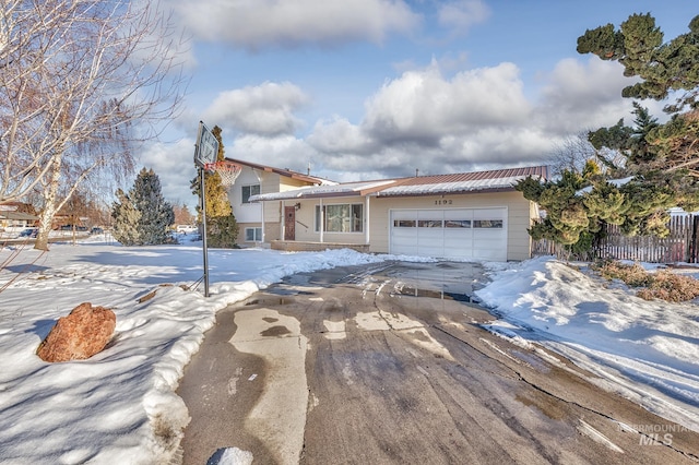 tri-level home with an attached garage, fence, and concrete driveway