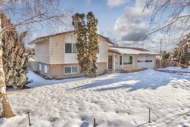 snow covered house with a garage and brick siding