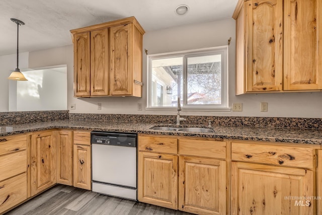 kitchen featuring dark stone counters, decorative light fixtures, dishwasher, and a sink