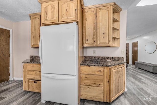 kitchen with light wood-style floors, light brown cabinetry, freestanding refrigerator, dark stone counters, and open shelves