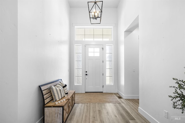 entryway with light wood-style flooring, baseboards, and a chandelier