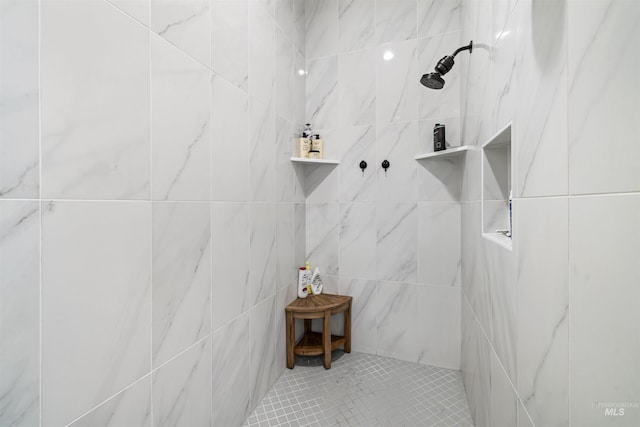 full bathroom with a tile shower, tile patterned flooring, and tile walls