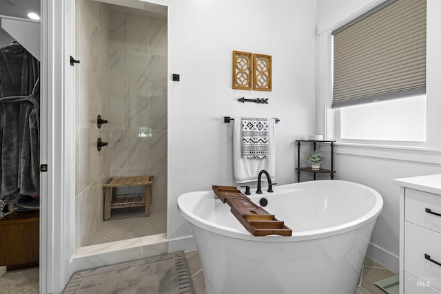 full bath featuring a stall shower, a freestanding bath, vanity, and baseboards