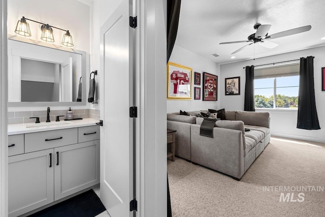 bathroom featuring ceiling fan, vanity, and tasteful backsplash