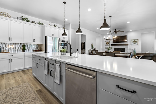 kitchen with stainless steel appliances, a sink, recessed lighting, light countertops, and light wood finished floors
