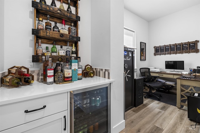 indoor dry bar featuring beverage cooler and light wood-style floors