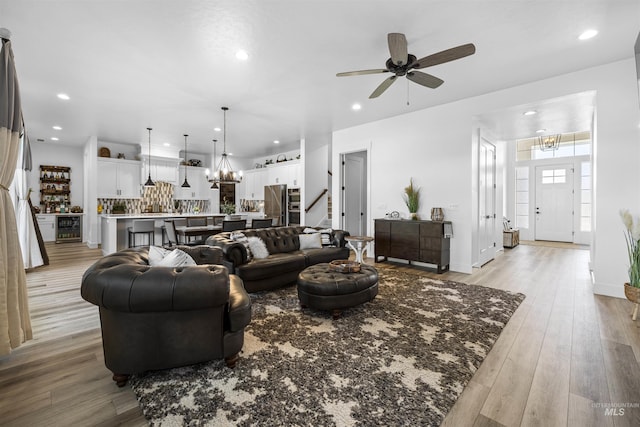 living area featuring a chandelier, stairway, recessed lighting, wine cooler, and light wood-style flooring