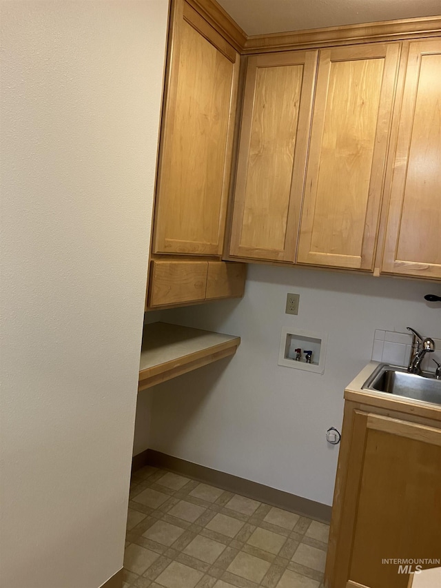 laundry room featuring a sink, baseboards, cabinet space, and light floors