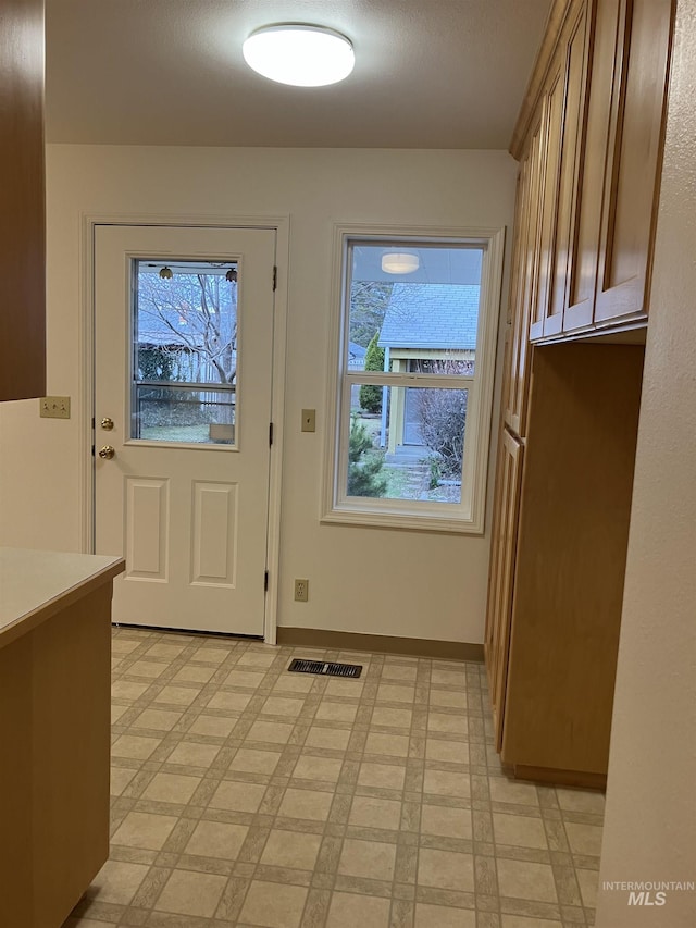 doorway to outside featuring visible vents, baseboards, and light floors