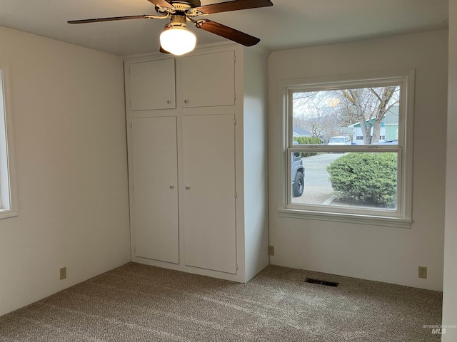 unfurnished bedroom featuring a ceiling fan, light colored carpet, visible vents, and a closet