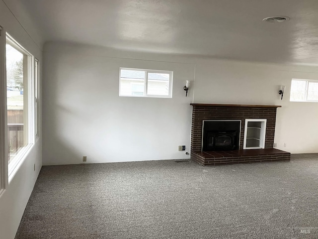 unfurnished living room featuring visible vents, carpet, and a brick fireplace