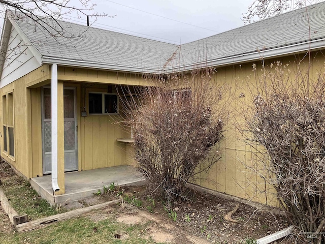 view of side of home with roof with shingles