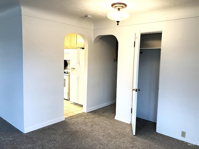 interior space featuring arched walkways, white fridge with ice dispenser, and light carpet