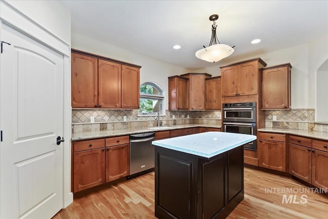 kitchen featuring stainless steel dishwasher, double oven, light wood finished floors, and a sink