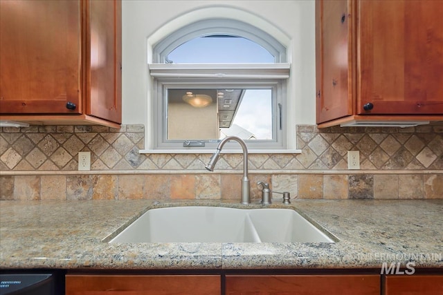 kitchen featuring light stone counters, backsplash, and a sink