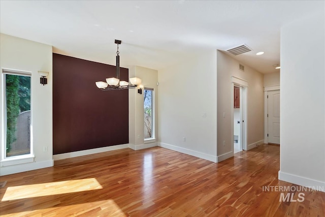 interior space with a chandelier, visible vents, baseboards, and wood finished floors