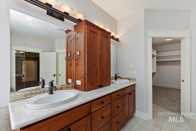 bathroom with a sink, baseboards, double vanity, and tile patterned floors