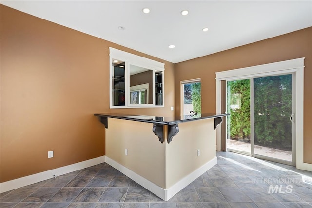 kitchen with a kitchen bar, baseboards, and dark countertops