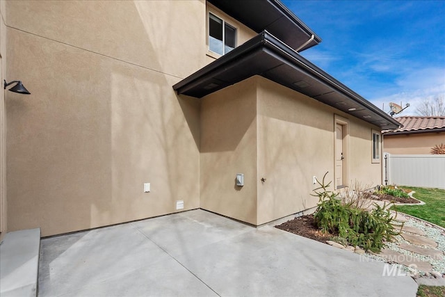 view of home's exterior with stucco siding, a patio, and fence