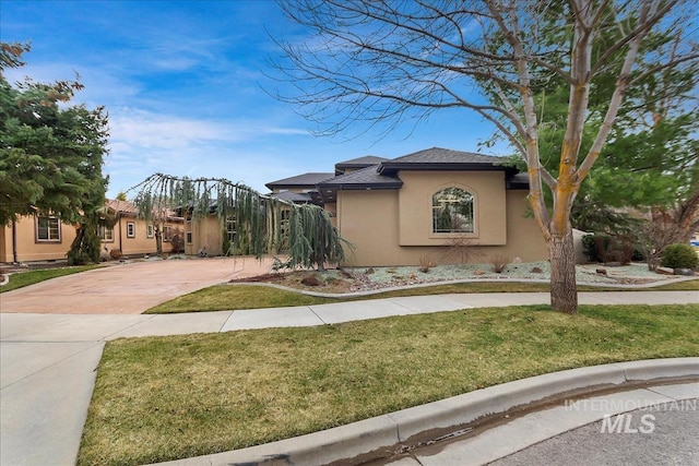 view of side of property with stucco siding, a lawn, concrete driveway, and a shingled roof