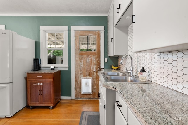 907 3rd St, Lewiston, ID 83501 - kitchen with freestanding refrigerator, backsplash, light wood-style floors, crown molding, and brown cabinetry