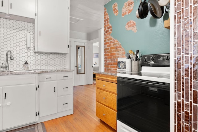 907 3rd St, Lewiston, ID 83501 - kitchen featuring range with electric cooktop, light wood finished floors, decorative backsplash, and white cabinetry