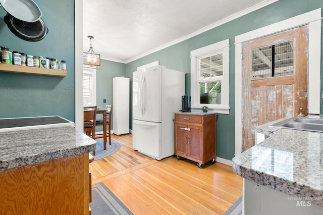 907 3rd St, Lewiston, ID 83501 - kitchen featuring freestanding refrigerator, brown cabinetry, light wood-style flooring, crown molding, and a chandelier
