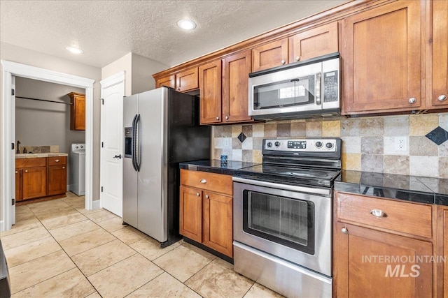 2476 S Amaya Ln, Boise, ID 83709 - kitchen with appliances with stainless steel finishes, washer / clothes dryer, brown cabinetry, tile countertops, and backsplash