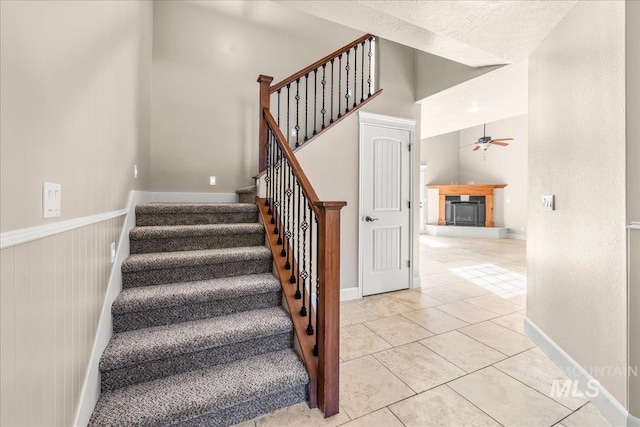 2476 S Amaya Ln, Boise, ID 83709 - stairs with ceiling fan, a glass covered fireplace, tile patterned flooring, and baseboards