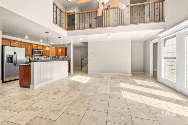 2476 S Amaya Ln, Boise, ID 83709 - kitchen with stainless steel appliances, open floor plan, a high ceiling, dark countertops, and brown cabinetry