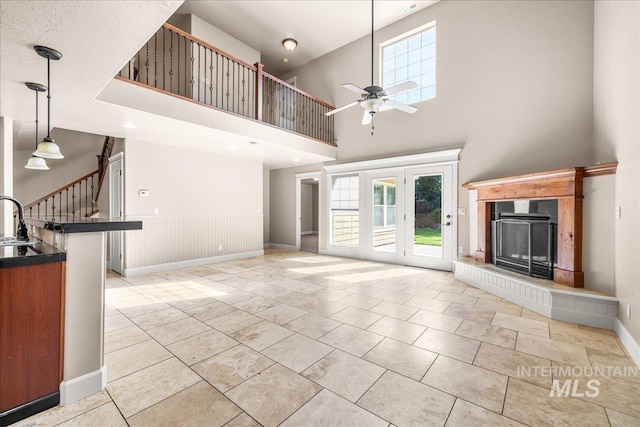 2476 S Amaya Ln, Boise, ID 83709 - unfurnished living room featuring ceiling fan, a fireplace with raised hearth, a sink, a towering ceiling, and stairs