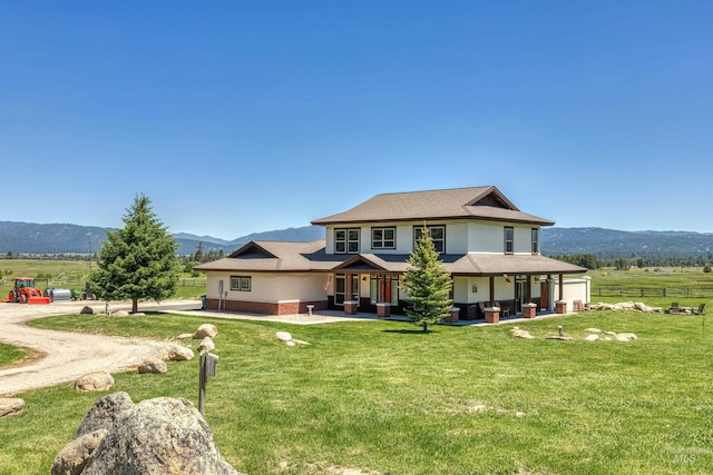 back of house with a yard, a mountain view, and a rural view