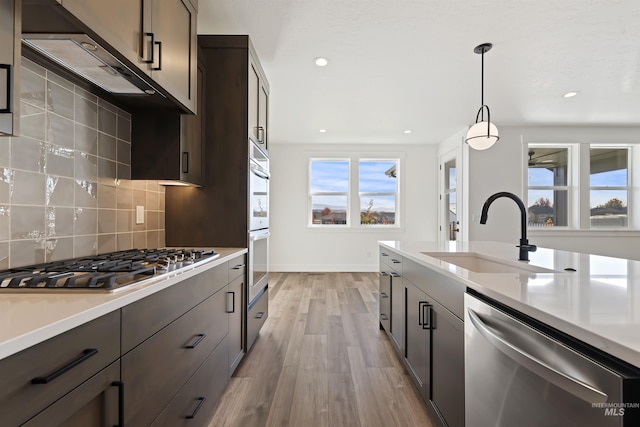 2358 E Monhegan Dr, Eagle, ID 83616 - kitchen featuring stainless steel appliances, a sink, light countertops, light wood-style floors, and tasteful backsplash