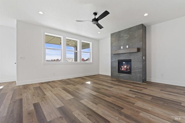 2358 E Monhegan Dr, Eagle, ID 83616 - unfurnished living room featuring wood finished floors, ceiling fan, a tiled fireplace, baseboards, and recessed lighting