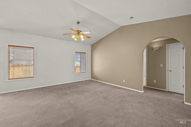 empty room with carpet floors, a textured ceiling, vaulted ceiling, and ceiling fan