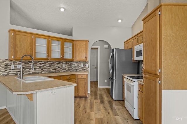 kitchen featuring white appliances, kitchen peninsula, sink, and light hardwood / wood-style flooring