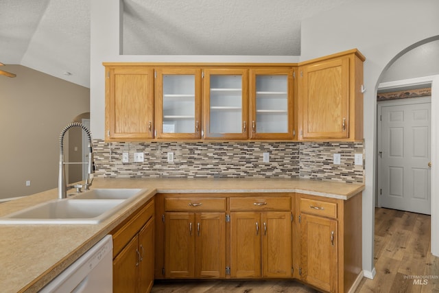 kitchen featuring lofted ceiling, sink, dishwasher, decorative backsplash, and light wood-type flooring